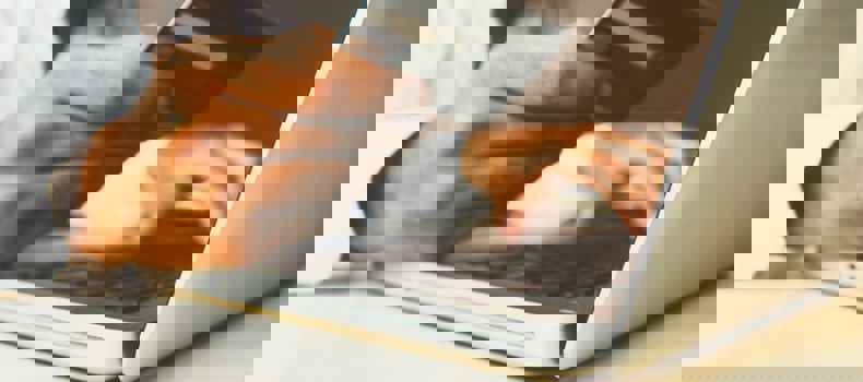 Person holding a credit card while using a laptop.